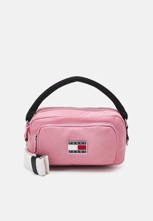 Sac banane en nylon rose avec sangle noire, doté d'une poche zippée à l'avant et d'un patch logo de la marque. Forme rectangulaire compacte avec texture lisse.