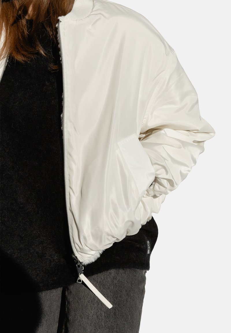 Weiße Bomberjacke mit glänzender Satin-Oberfläche, geribbeltem Kragen und elastischen Bündchen. Detail: silberner Reißverschluss und seitliche Taschen.