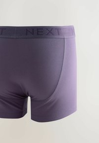 Lila boxernadrág sima, rugalmas anyagból, mintás derékrésszel, melyen a "NEXT" márkaneve szerepel. Díszített élek és testhez álló fazon jellemzi.