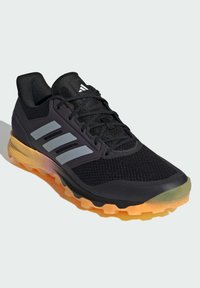 Černá sportovní bota s síťovinovým svrškem, reflexními stříbrnými pruhy a vícebarevnou podrážkou s přechodem z oranžové do průhledné.
