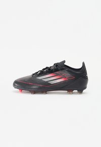 Black soccer cleat with a sleek design, featuring red accents, textured upper, and multiple studs for traction on the sole.