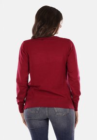 Maglione rosso realizzato in morbido tessuto a maglia, con maniche lunghe, scollatura rotonda e orlo a coste, progettato per una silhouette aderente.