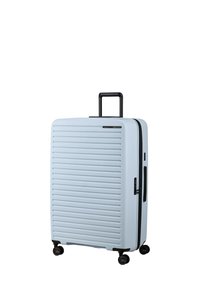 Light blue hard-shell suitcase with horizontal ridges, a retractable black handle, and four black wheels for mobility. Zipper closure on the side.