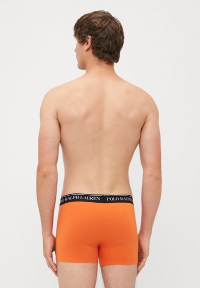 Oranžiniai apatiniai kelnaitės su juodu elastingu juosmeniu, kuriame yra tekstas "POLO RALPH LAUREN", prispaudžiantis kirpimas, lygus audinys ir minimalistinis dizainas.