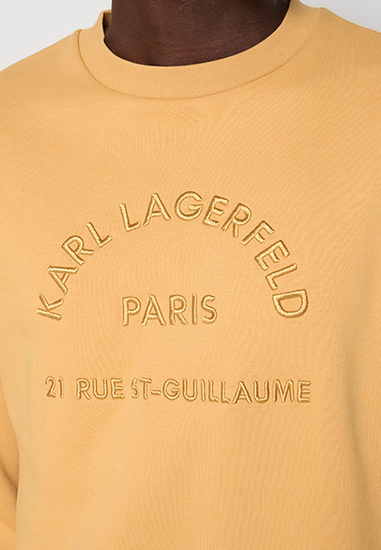 Gelber Baumwoll-Sweatshirt mit erhabenem Stickerei von "KARL LAGERFELD PARIS 21 RUE ST-GUILLAUME" in einer geschwungenen Anordnung. Rundhalsausschnitt.