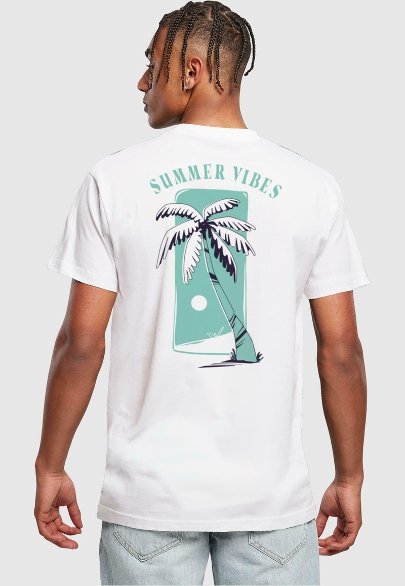Hvit T-skjorte med et palmetre-grafikk i teal og svart med teksten "SUMMER VIBES" over, kortermet og med en avslappet passform.