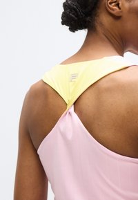 Mouwloze jurk met een roze lijfje en gele, gestructureerde bandjes. Heeft een kruisbandontwerp aan de achterkant en een klein logoaccent op het bandje.