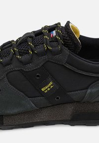 Sneakers neri caratterizzati da un mix di materiali, tra cui rete e camoscio, con dettagli gialli, suola robusta e occhielli rinforzati.