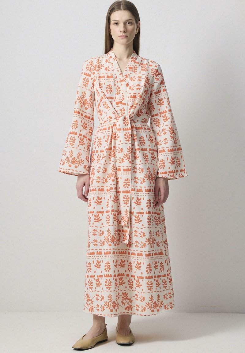 Robe longue imprimée en tissu léger, ornée de motifs botaniques orange et d'un design croisé, avec des manches larges et une taille nouée.