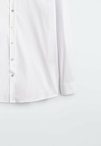 White long-sleeve button-up shirt with a smooth texture, featuring a classic collar, silver buttons, and a curved hemline.