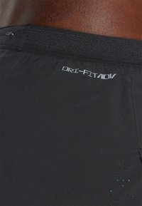 Svarte Dri-FIT shorts med en teksturert midjebånd og subtile perforeringer i et gradientmønster nær kanten. Har "DRI-FIT ADV" logo.