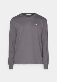 Harmaa pitkähihainen t-paita, joka on valmistettu pehmeästä ja kevyestä kankaasta. Siinä on pyöreä kaula-aukko ja pieni logo rinnassa. Yksinkertainen, yksivärinen muotoilu.