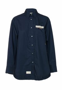 Tengerészkék, könnyű anyagból készült ing gombos elülső résszel, csipke és szalag díszítéssel a mellzsebnél, fodros szegéllyel.