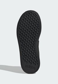 Czarna gumowa podeszwa buta z wzorem plastra miodu i fakturowaną powierzchnią. Z przodu znajduje się wytłoczona logo marki na pięcie.