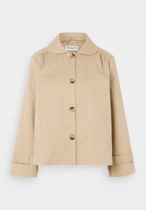 Beige katoenen jas met een ronde kraag, sluiting met knopen aan de voorkant en twee zijzakken. Kenmerkende plooidetails op de schouders en manchetten.