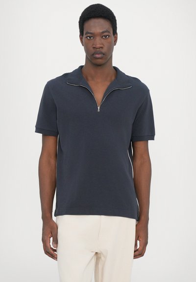 Navy short-sleeve polo shirt with a zip collar, made from soft cotton. Features a relaxed fit and subtle side seams for added detail.