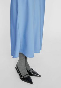 Svetlo modra obleka z flowing silhueto, v kombinaciji s sivo obutvijo in črnimi lakastimi čevlji s špičastimi noski in sponkami.