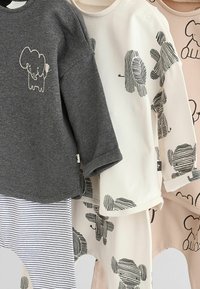 Harmaa, valkoinen ja vaaleanpunainen lastenvaatetus, jossa on norsugrafiikoita ja raidallisia kuvioita. Pehmeä puuvillamateriaali, pyöreä kaula-aukko ja napit.