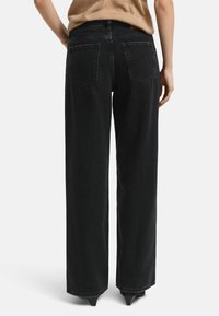 Pantalons en denim noir à taille haute, à jambe large, avec une texture lisse, cinq poches et des détails de couture subtils à la taille et à l'ourlet.