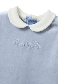 Camisa de velour azul claro con cuello blanco y texto bordado "Soy adorable" en azul más claro. Cierre de botones en el cuello.