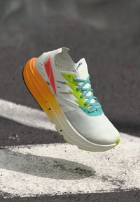 Zapatilla de correr ligera con una parte superior de malla blanca, cordones turquesas, acentos en verde neón y naranja, y una suela amarilla texturizada.