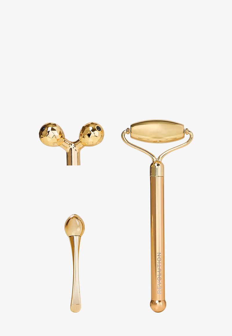 Zestaw złotych wałków do twarzy, w skład którego wchodzi większy wałek z płaską owalną główką, mniejszy wałek w kształcie kulki oraz zwężony masażer, wszystko eleganckie i błyszczące.