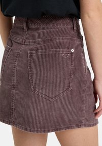 Corduroy rok in stofroze, met verticale strepen, een aansluitende taille, een achterzak met hartborduursel en accenten van metalen hardware.