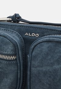 Portefeuille en tissu bleu texturé avec deux compartiments zippés et logo argenté de la marque ALDO près du curseur de la fermeture éclair.