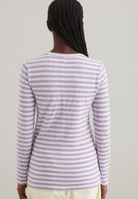 Gestreiftes Langarmoberteil mit lila und weißen horizontalen Streifen, weichem Stoff, gerundetem Halsausschnitt und taillierter Passform. Sichtbares Nahtdetail in der Mitte.