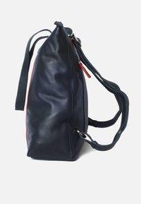 Leren handtas in navy blauw met een gestructureerd ontwerp, dubbele handvatten, een rode ritssluiting, en een gladde, textuur oppervlakte.