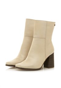 Stivali alla caviglia in pelle beige con una texture liscia, punta quadrata e tacco a blocco marrone. Design semplice con cuciture minime e senza hardware visibile.