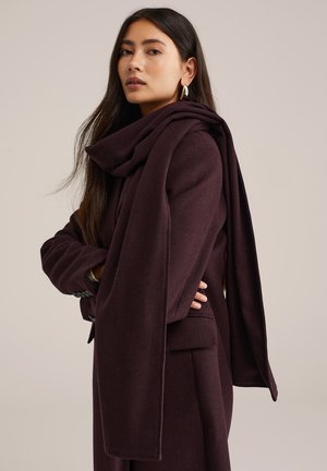 Manteau en mélange de laine bordeaux avec un col drapé et des manches longues. Caractéristiques : coupe ajustée, texture subtile et design épuré et minimaliste.