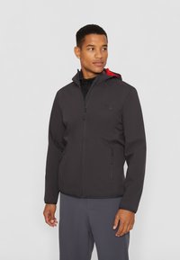 Zwarte zip-up jas met een rode binnenkant van de capuchon, voorzien van twee zijzakken en een zachte stoftextuur, ontworpen voor comfort en warmte.