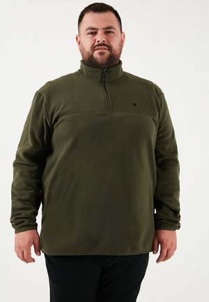 Green fleece pullover with a quarter-zip, textured fabric, and black accent logo on the chest. Long sleeves with a relaxed fit.