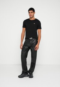 Fekete rövid ujjú póló kis logóval, fekete bőrcargo nadrággal, zsebekkel és övvel párosítva. Fekete sportcipő.