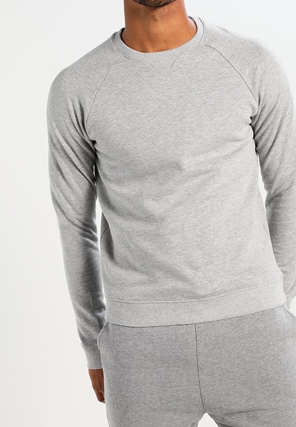 Felpa grigia con maniche raglan, realizzata in morbido misto cotone. Presenta una scollatura rotonda e polsini e orlo a costine per una vestibilità aderente.