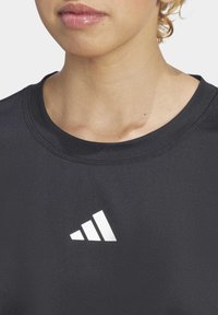 Juodas sportinis marškinėliai su apvaliu iškirpimu, su baltu Adidas logotipu ant krūtinės, pagaminti iš lygaus, tamprios medžiagos.