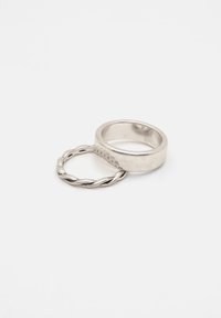 Vridna silverring och slät silverring, båda med en polerad yta. Den vridna ringen har en texturerad kant, medan den andra är enkel.