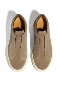Scarpe slip-on in suede beige con inserti elastici laterali e suole in gomma crema, caratterizzate da cuciture tonali e una superficie liscia nella parte superiore.