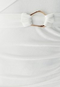 Weißes Stoffkleid mit einem geknoteten Gürtel und einem goldfarbenen Metallelement. Das Material hat eine weiche, strukturierte Oberfläche mit dezenten Drapierungen.