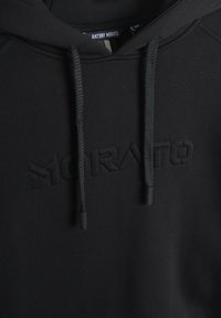 Sudadera negra con un acabado texturizado, presenta un logo "MORATO" en tonalidad en el frontal, cordones ajustables y una tela suave.