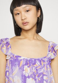 Vestido floral roxo com alças franzidas e decote em forma de coração, apresentando um tecido leve e suave com um padrão em aquarela em branco e detalhes em laranja.