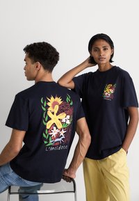 Marineblå bomulds t-shirts med blomstergraphics på ryggen og venstre bryst. Modellerne er placeret ryg-til-ryg og side-til-side.