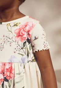 Rochie cu model floral și textură striată, având flori roz și albastre pe un fundal alb-crem. Mâneci scurte cu volănașe și talie adunată.