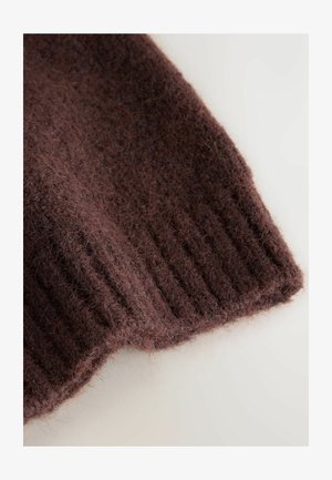 Pruuni kootud kangasäär koos pehme, udusena ja soonilise mustriga. Materjal näib soe ja mugav, natuke ebaühtlase viimistlusega.