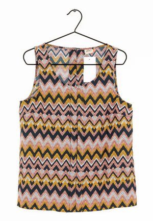 Sleevless topp på en svart klädgalge, med ett zickzackmönster i rosa, vitt, gult och svart. Materialet verkar lätt och har en jämn textur.