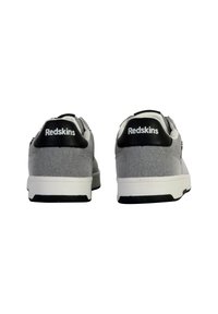 Zapatillas de tela gris con acentos en blanco y negro. Cuentan con material de lona, una suela resistente y una marca en el talón trasero.