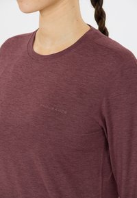 Burgunderfärgad långärmad skjorta med rund halsringning. Tillverkad av textil med struktur och har en subtil "ENDURANCE"-logotyp på bröstet.