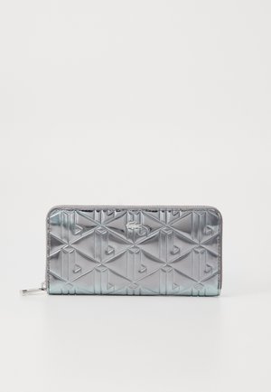 Cartera con cremallera metálica plateada, con un patrón geométrico en relieve, que presenta un acabado texturizado y herrajes plateados. Forma rectangular compacta.