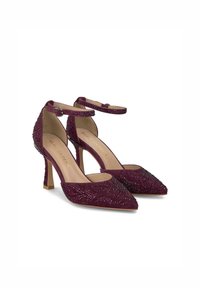 Talons en suède bordeaux avec un bout pointu et une lanière à la cheville à l'arrière, ornés de perles délicates et d'un talon modeste. Doublure intérieure lisse.